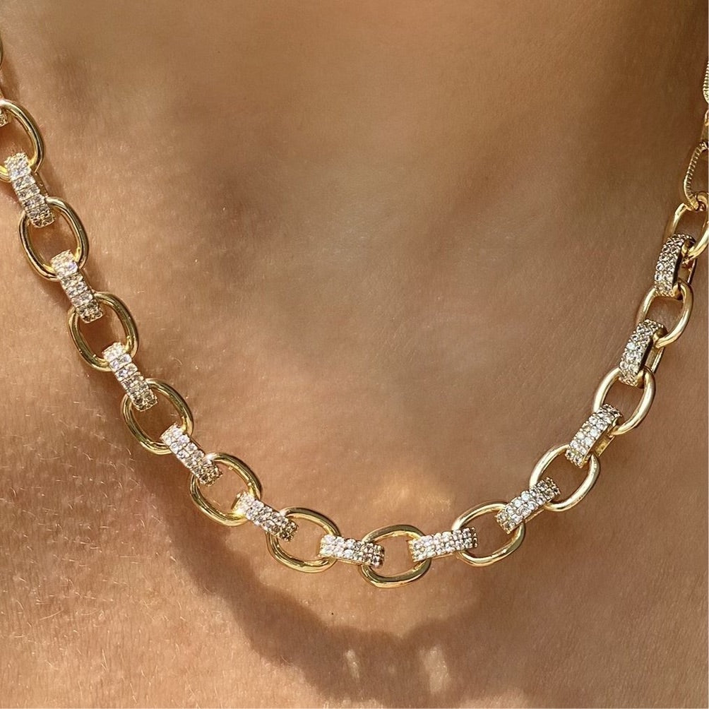 woman wearing yellow gold oval link necklace with patterns of one cubic zirconia pave link and one solid gold plated link